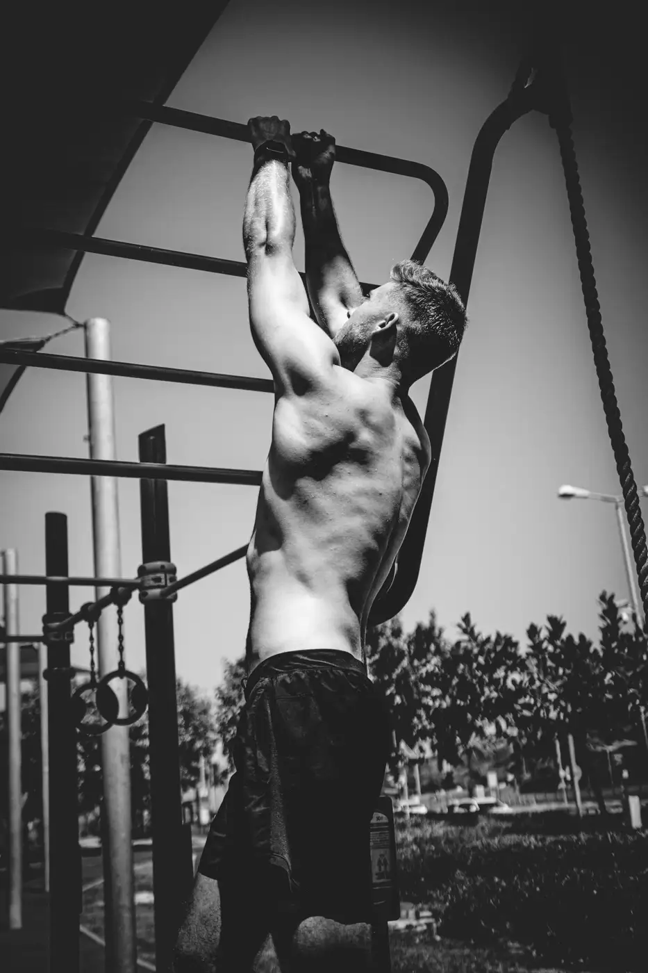 Atleet doet een muscle-up aan een rek in de buitenlucht